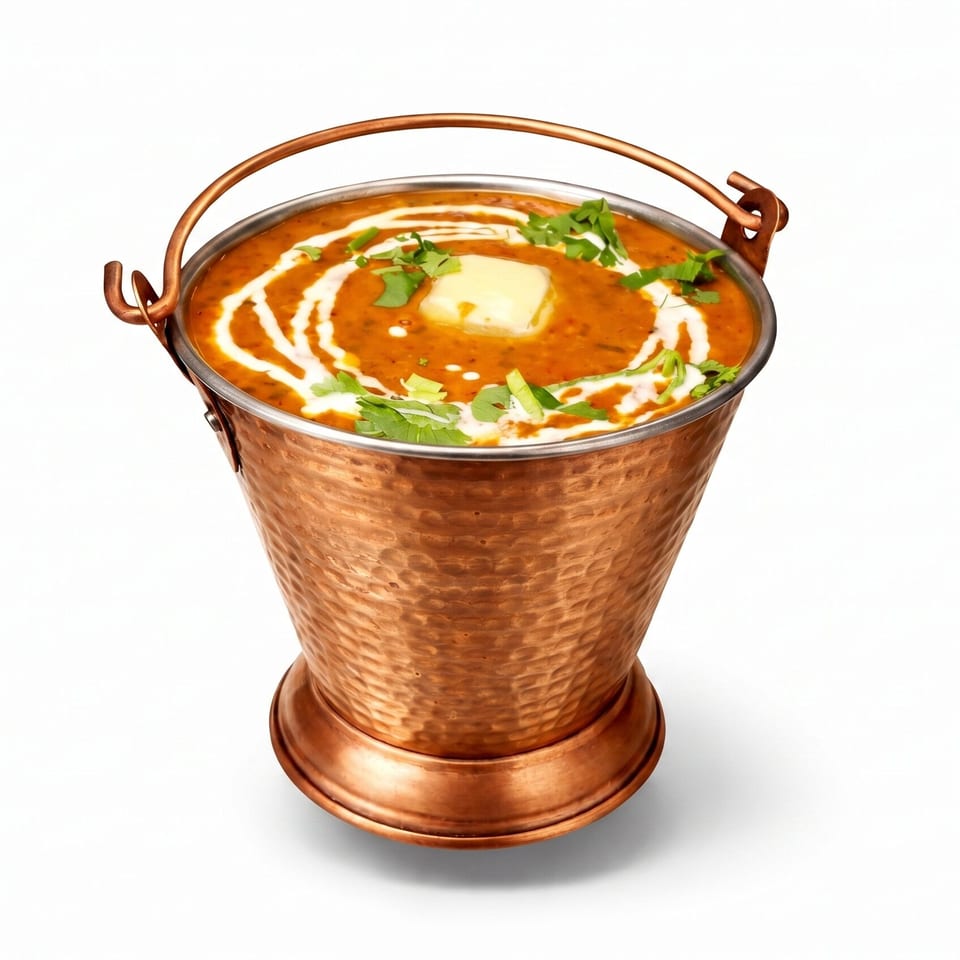 Dal Makhani, an Indian lentil dish, in a hammered copper bucket with butter and cilantro.