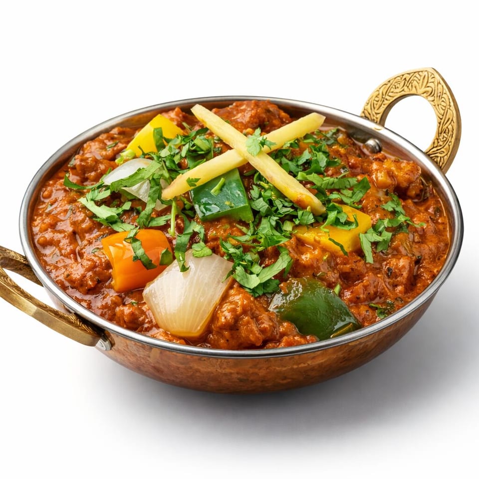 Copper serving dish filled with rich curry, colorful peppers, onions, cilantro, and crossed ginger strips.
