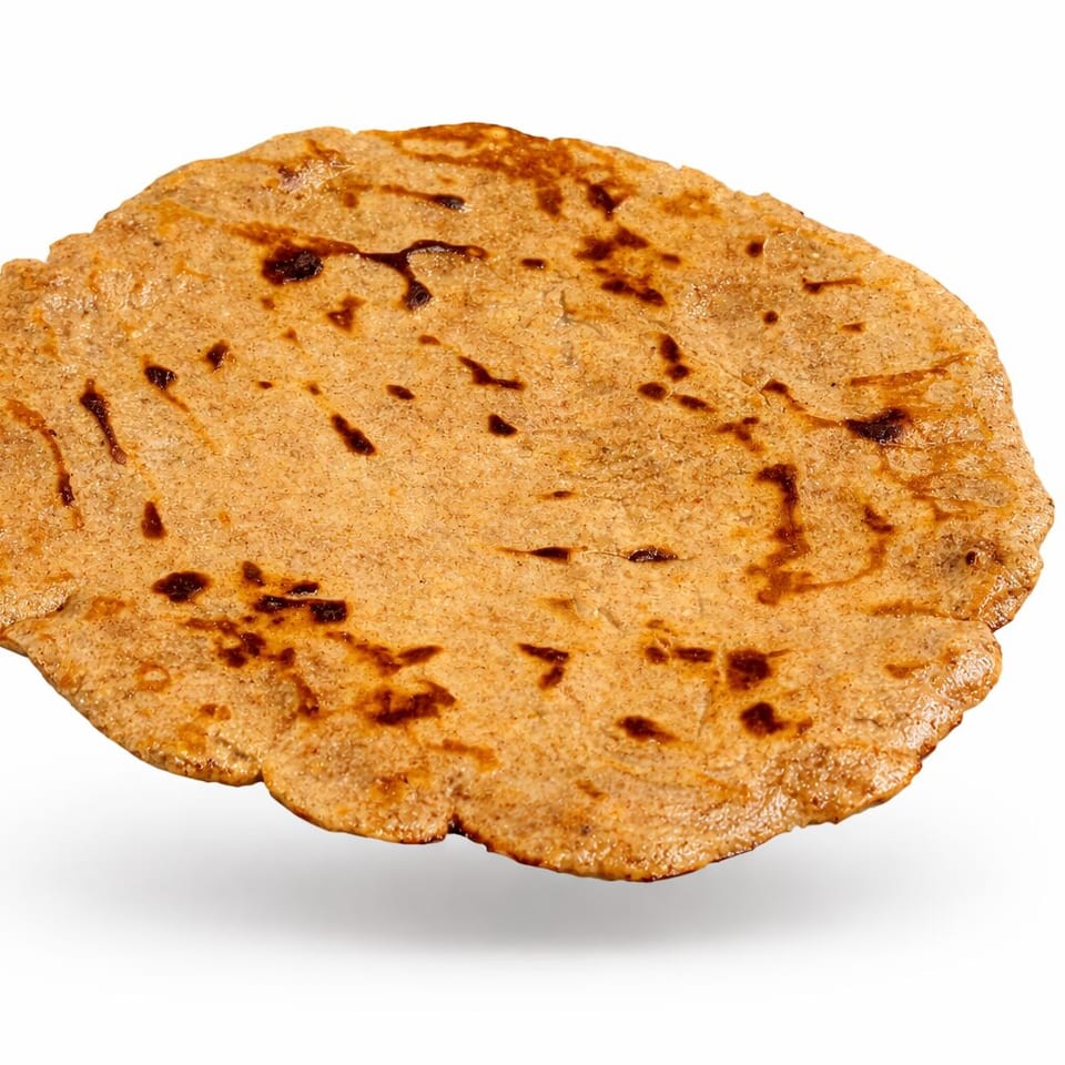Golden-brown grilled flatbread with irregular edges and toasted spots, displayed against a white background.